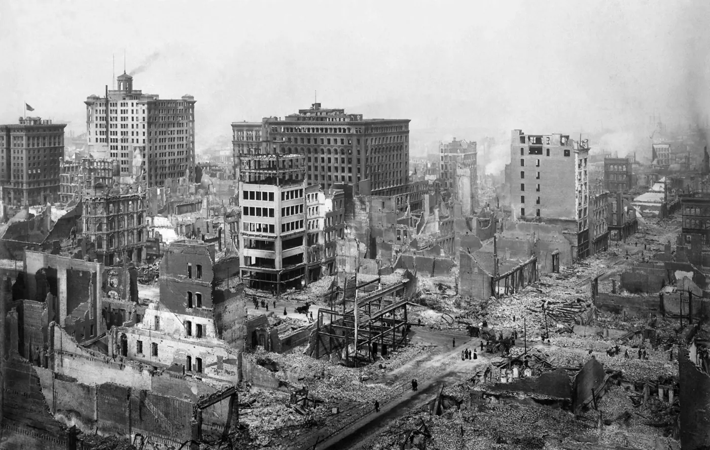 地震と火災のあとのサンフランシスコ市街の白黒写真。焼け落ちた建物が通りの両側に続き、遠くまで瓦礫が広がっている