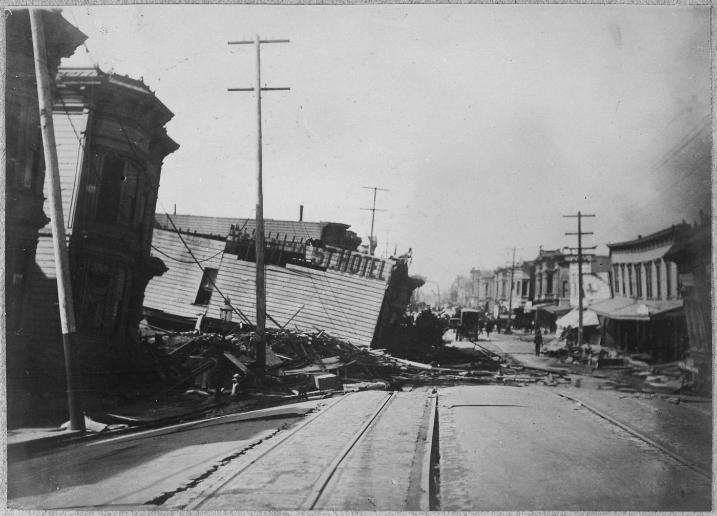 地震で地盤ごと沈み込み倒壊したValencia Street Hotelの白黒写真。木造の建物が大きく傾いて崩れ、周囲に人が集まっている